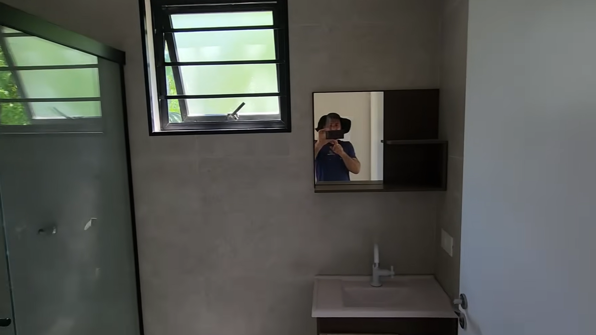 Banheiro completo com box de vidro, bancada e revestimento cimentício