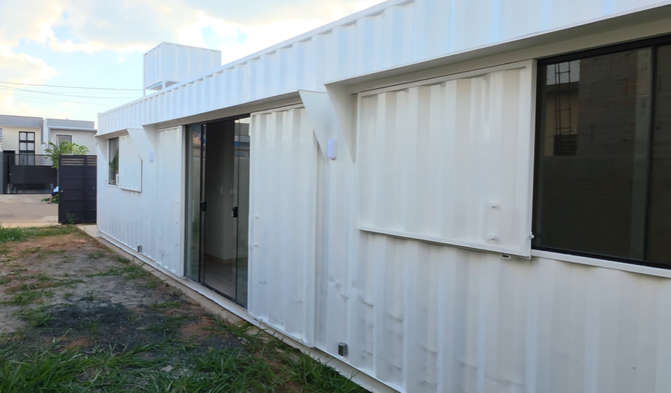 Vista lateral do container branco com porta de correr em vidro aberta