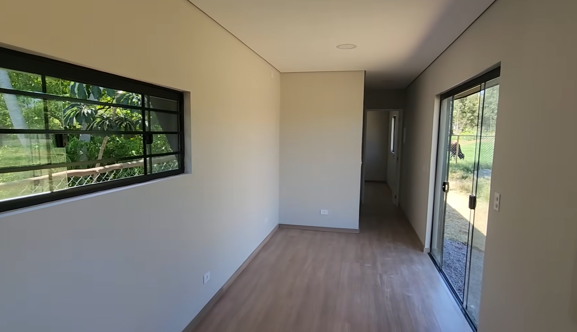 Sala ampla com piso em madeira e vista para o exterior