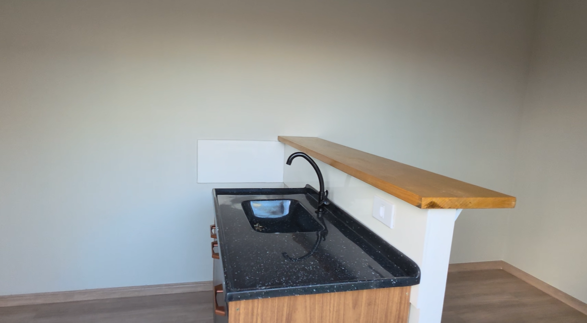 Cozinha americana com bancada em granito preto e balcão em madeira