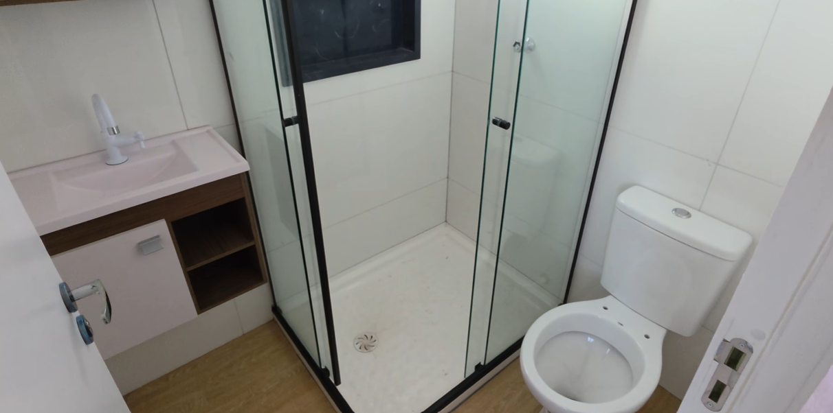 Banheiro completo com box de vidro, gabinete e vaso sanitário
