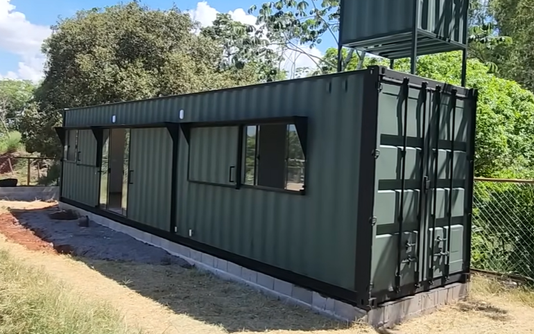 Fachada frontal do container 30 m² em verde militar com portas de vidro