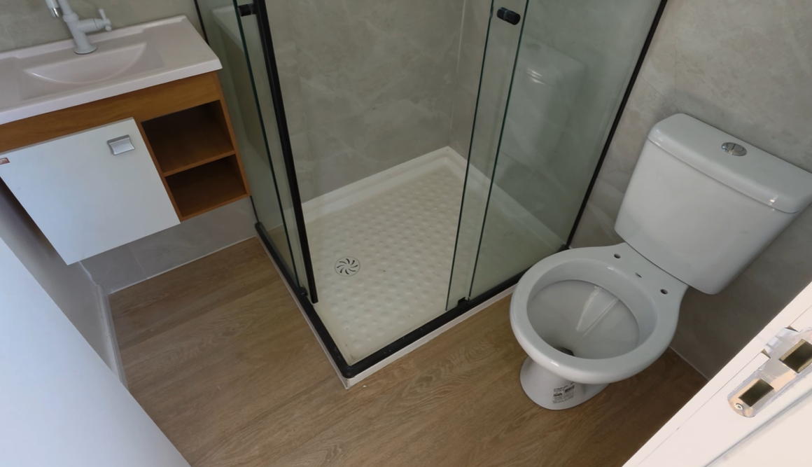 Banheiro completo com box de vidro e piso em madeira